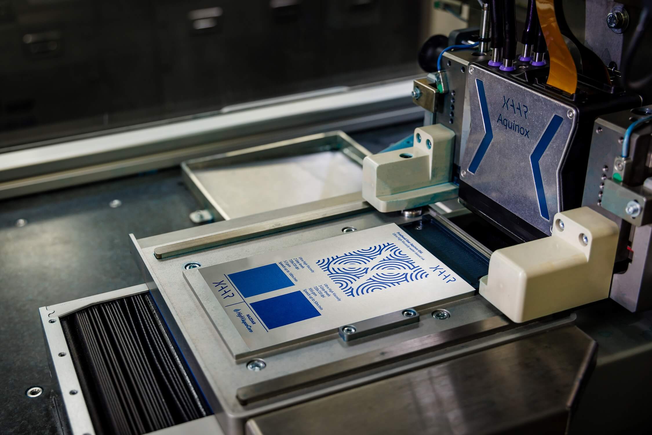 Close-up of Xaar's Aquinox printhead using high-viscosity aqueous inks to produce vibrant, detailed prints on a corrugated substrate, demonstrating sustainable digital printing technology.