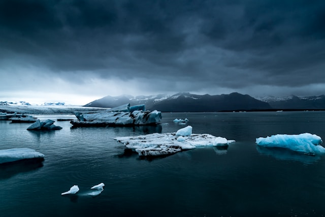 Icebergs floating in a glacial lagoon beneath dark skies in Iceland, capturing the raw, natural beauty that defines Iceland ecotourism.
