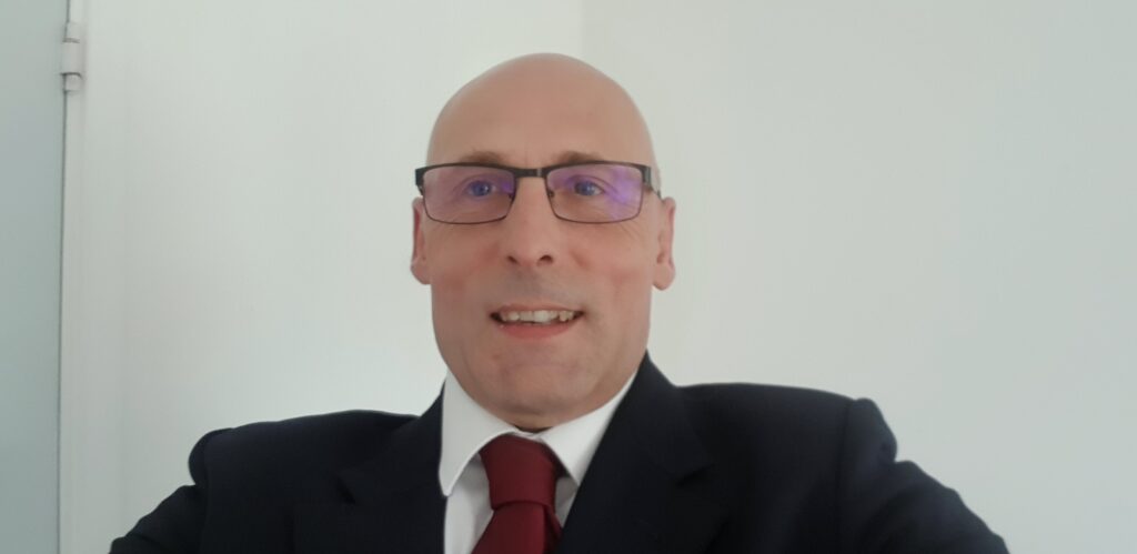 Carl Jerromes, a participant in Stonewater’s Sustainable Futures programme, supporting educational growth in sustainability, wearing a suit and tie, smiling against a plain white background.