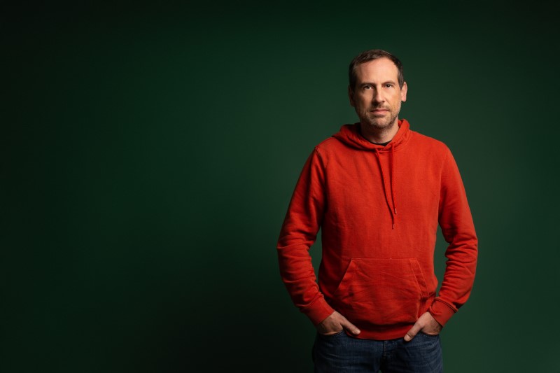 Gaël Duval, CEO of Murena, standing against a green backdrop wearing a red hoodie, representing Murena's commitment to the importance of data security and ethical tech innovation.