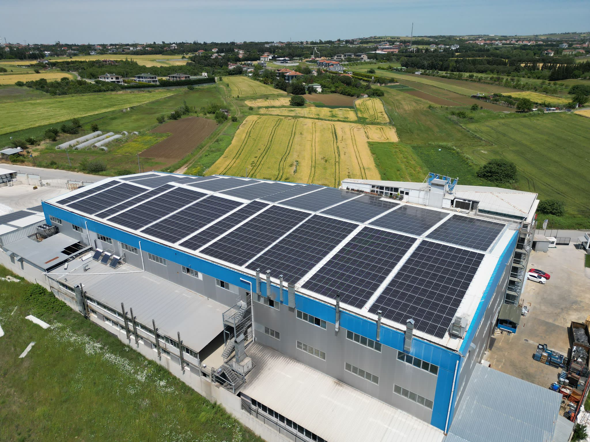 Eco sustainability at ASSA ABLOY: Aerial view of the Rychnov factory with solar panels on the roof, showcasing renewable energy efforts in a green landscape.