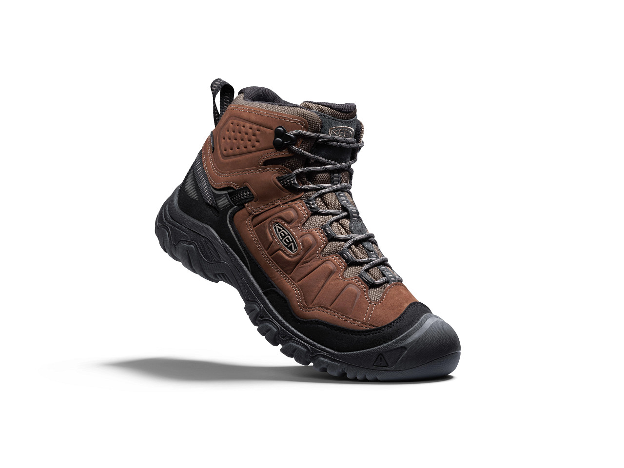 A brown and black KEEN sustainable hiking boot, the Targhee IV Mid, displayed against a white background, showcasing its rugged design and eco-friendly materials.