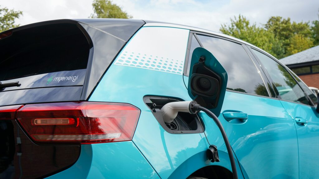 An electric car plugged into a charging station, illustrating the question: why can't electric cars charge themselves despite advanced technology.