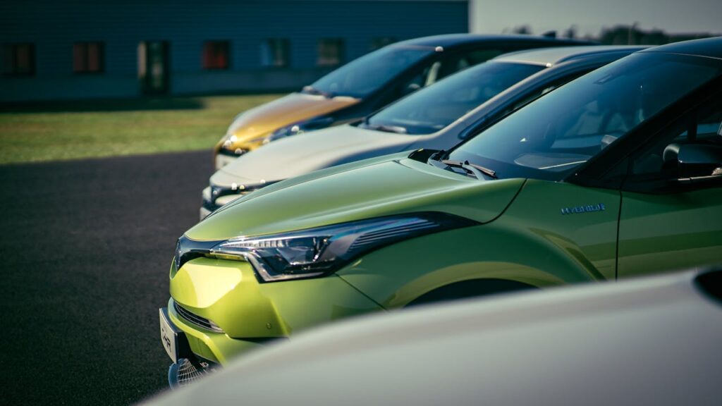 A row of modern electric cars in assorted colors parked outdoors, illustrating the concept of “why cant electric cars charge themselves.”