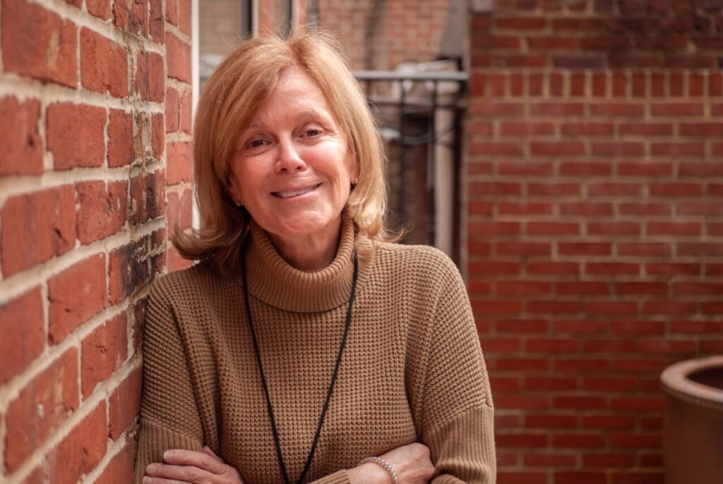 Earth Day President Kathleen Rogers leaning against wall smiling 