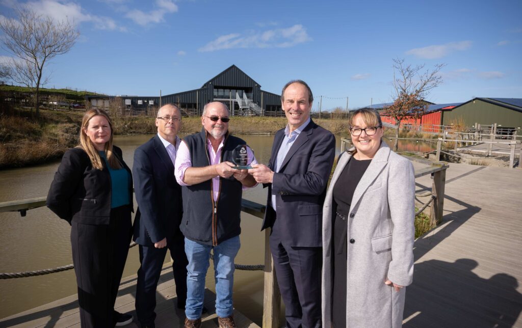 Geraint and Christine Thomas of Bargoed Farm receiving the NatWest Green Business of the Year award for their sustainable business model, alongside NatWest representatives at their eco-friendly caravan park in Ceredigion.