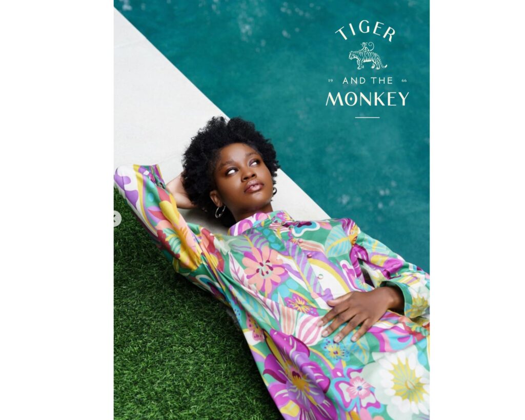 Model reclining poolside in a bold floral dress by Tiger and the Monkey, representing eco luxury fashion with vibrant, sustainable design.