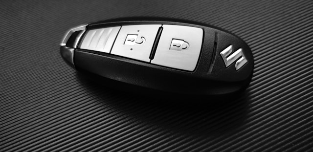 A close-up of a Suzuki car key fob on a textured black surface, illustrating what to do with old car keys that include electronic components.