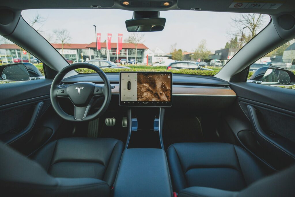 view of glove box and steering wheel of tesla from back seat