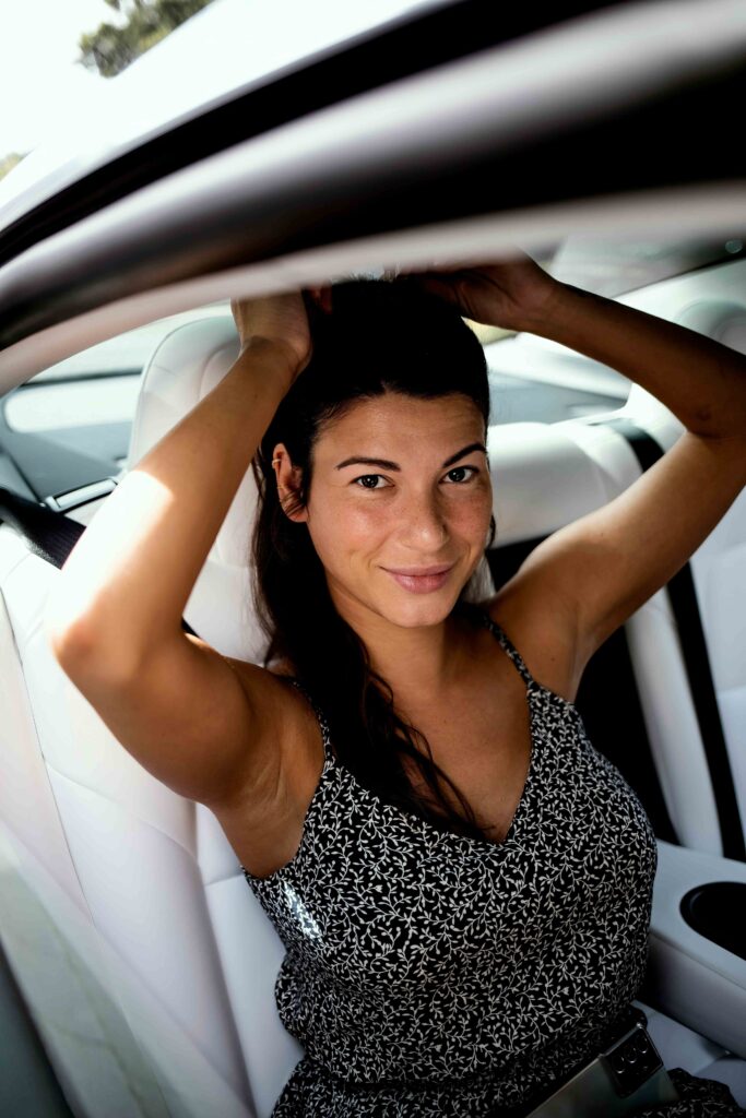 woman with arms up sitting on white tesla model 3 seats 