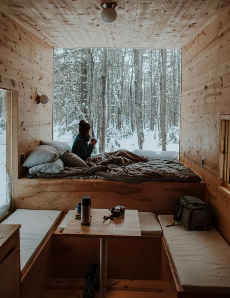 Tiny house inside looking out showing woman in bed and snow outside 