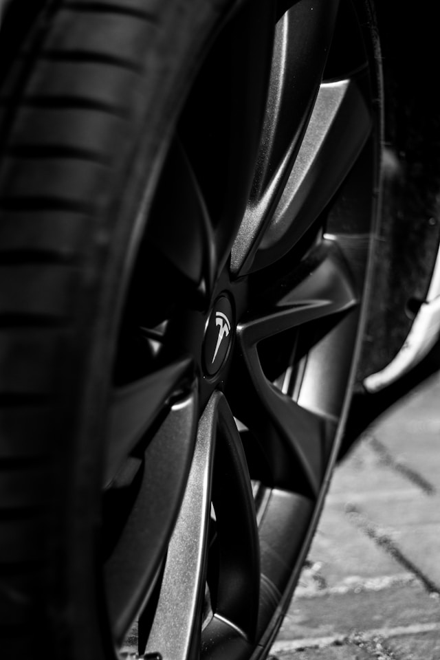 Black and silver Tesla wheel and tire captured in close-up, showcasing modern design and detail on a paved surface.