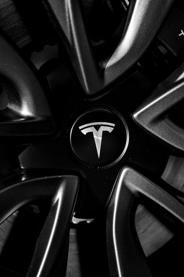 Close-up of a Tesla logo on a black wheel rim, emphasizing sleek design and quality for the best tires for Tesla.
