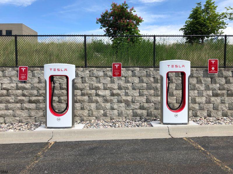 Two Tesla Supercharger stations in an empty parking lot, illustrating how much electricity does a Tesla use during charging at dedicated EV stations.