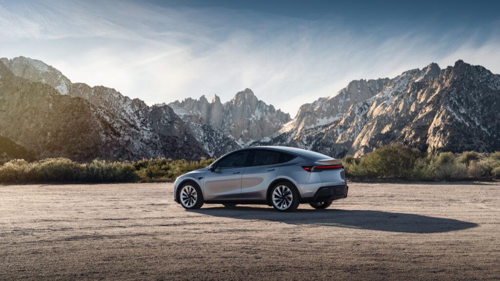 A silver Tesla Model Y parked in front of snow-capped mountains under a clear sky, showcasing its sleek design — ideal conditions for testing the best sunshade for Tesla Model Y in outdoor environments.