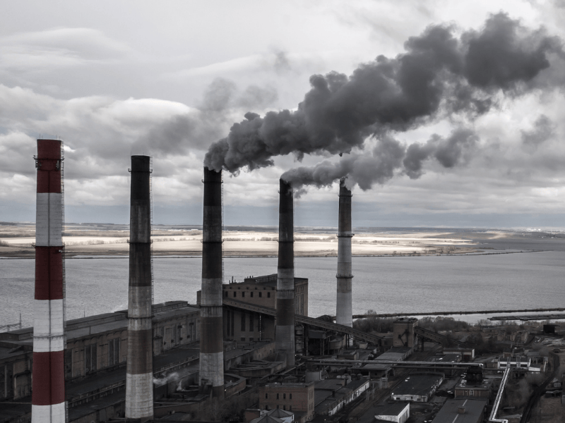Industrial smokestacks releasing heavy pollution into the air, representing the harmful effects of dirty energy in the United States.