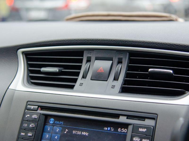 Close-up of a car dashboard showing air conditioning vents, hazard light button, and infotainment screen — concept related to how long can an electric car idle with AC on.