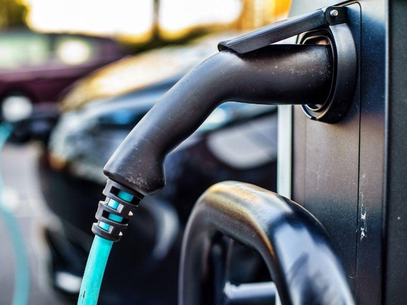Close-up of an electric vehicle charging plug connected to a charging station — concept related to how long can an electric car idle with AC on.