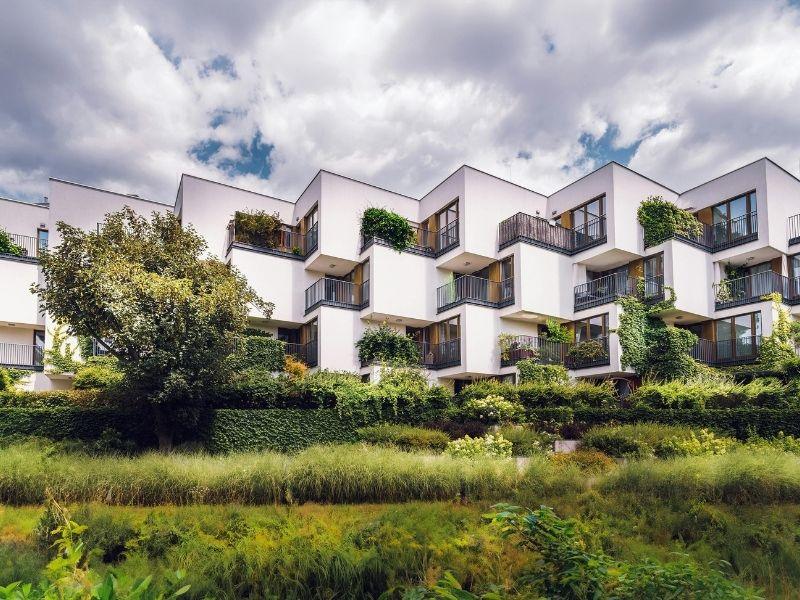 Modern apartment complex with geometric design and abundant greenery, showcasing Eco Brutalism and sustainable urban architecture.