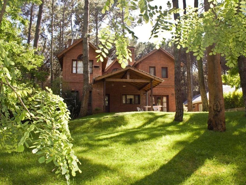 Beautiful brick house surrounded by tall trees and lush greenery, representing peaceful forest homes in a natural setting.