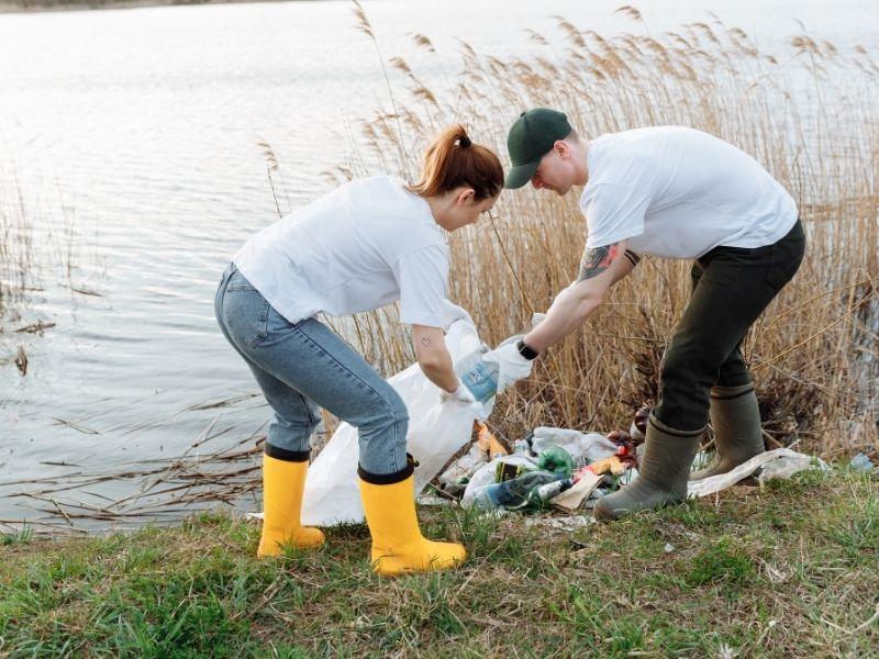 Volunteers cleaning trash along the bank of polluted rivers, removing plastic waste and debris to protect the environment.
