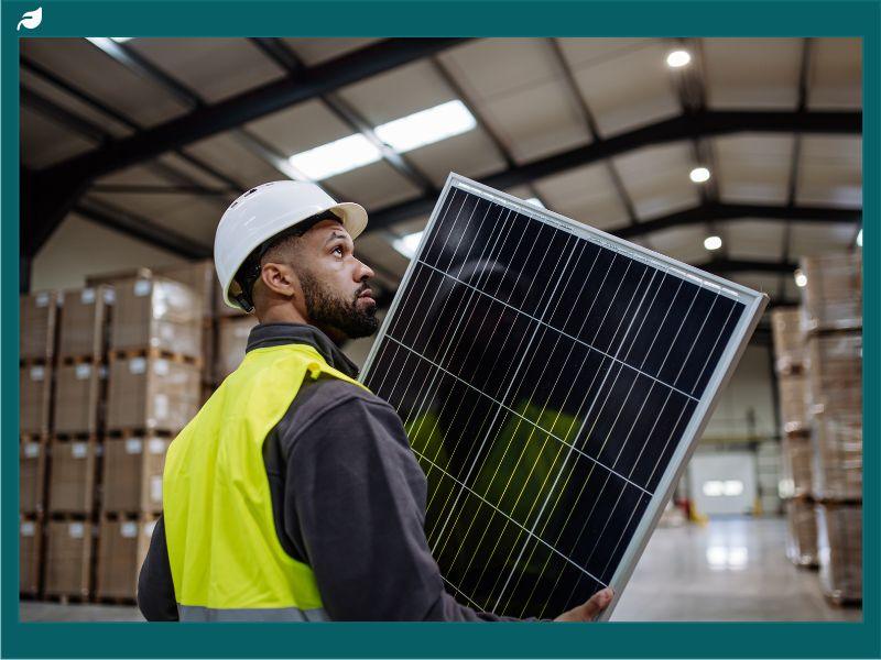 Worker carrying a solar panel in a warehouse as Senate Republicans tackle energy tax credits and renewable energy policies.