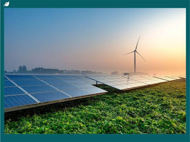 Solar panels and wind turbine at sunrise showcasing clean energy alternatives that reduce the environmental and health impacts of coal, such as air pollution, greenhouse gases, and respiratory diseases.