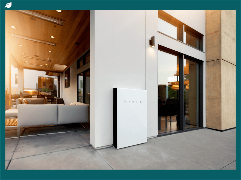 Tesla Powerwall installed on the exterior of a modern home, showing real-world application for comparing energy storage performance in the Enphase vs Tesla solar battery debate.