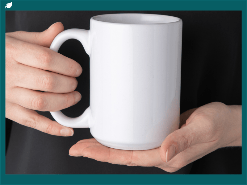 Person holding a plain white coffee mug, symbolizing support for elephant coffee conservation and sustainable coffee practices that help protect endangered elephants and their habitats.