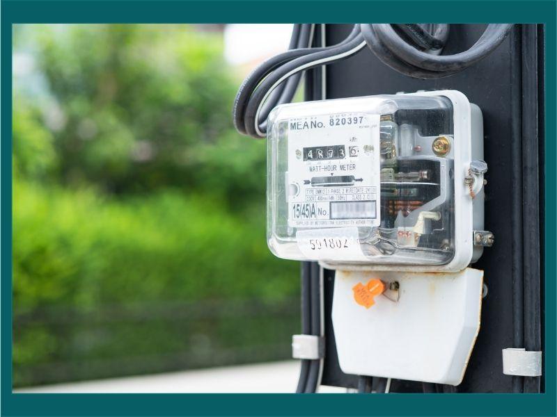 Electric utility meter mounted outdoors, displaying energy usage readings.