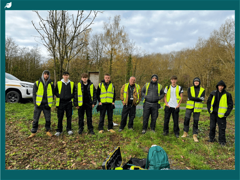 Stephenson College Carpentry and Joinery students wearing high-visibility vests standing together outdoors at Snibston Colliery Park during the boardwalk regeneration project.