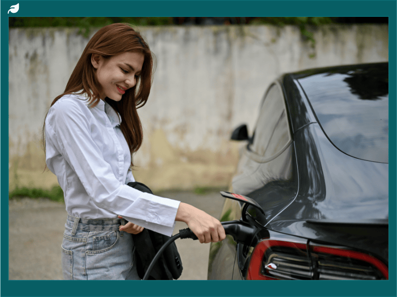 Woman plugging in an electric vehicle at home, illustrating factors that influence Tesla charger installation cost and residential EV charging setup.
