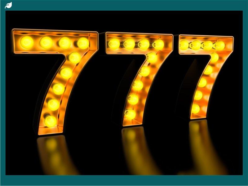 Glowing bulb-lit number 777 on dark reflective surface