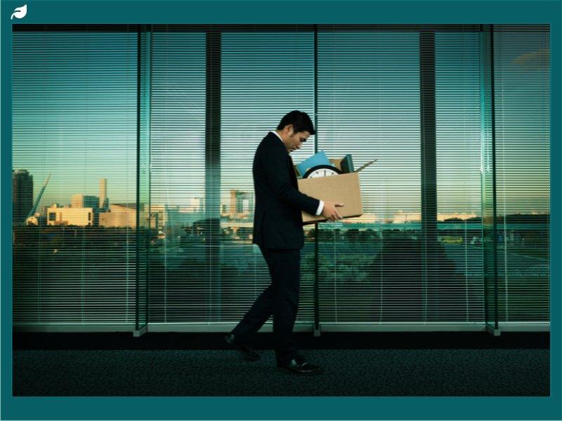 Businessman walking with cardboard box after being laid off