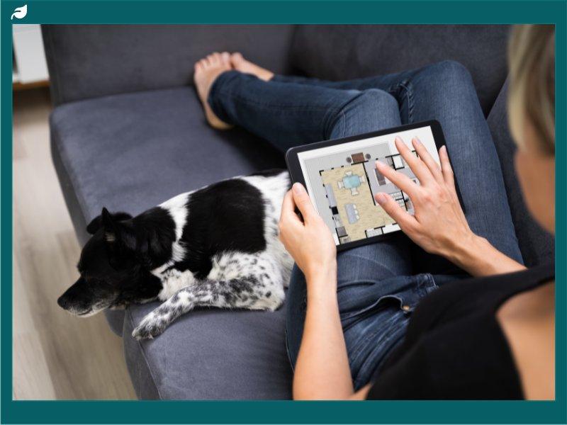 Woman reviewing digital home floor plan on tablet beside dog