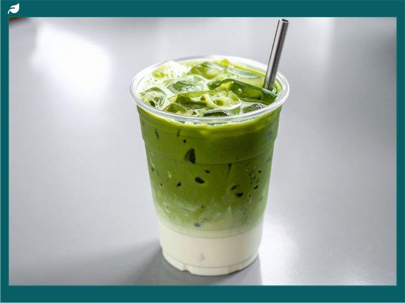 Iced matcha green tea latte layered over milk in clear cup