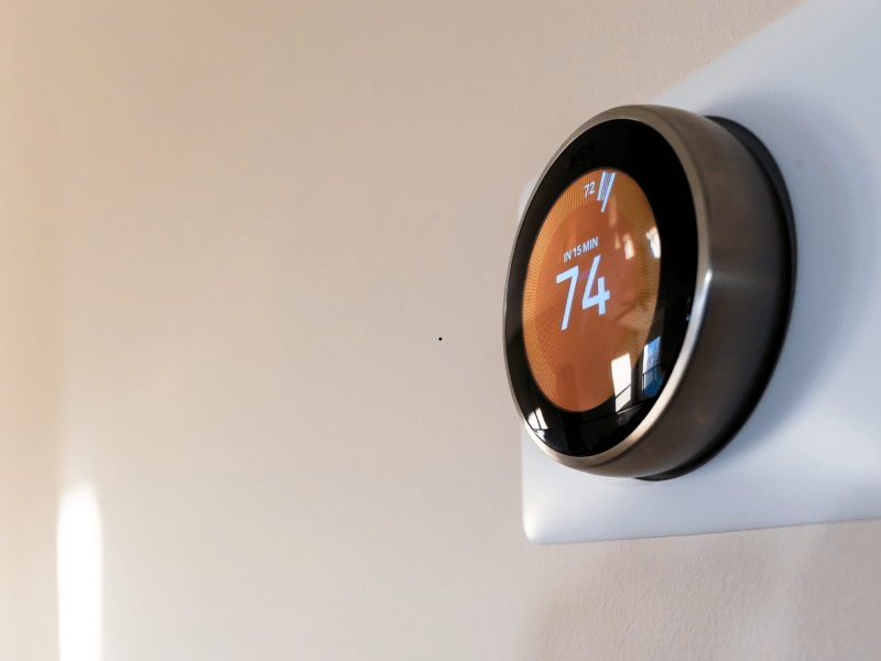 A smart thermostat displaying 74 in heating mode