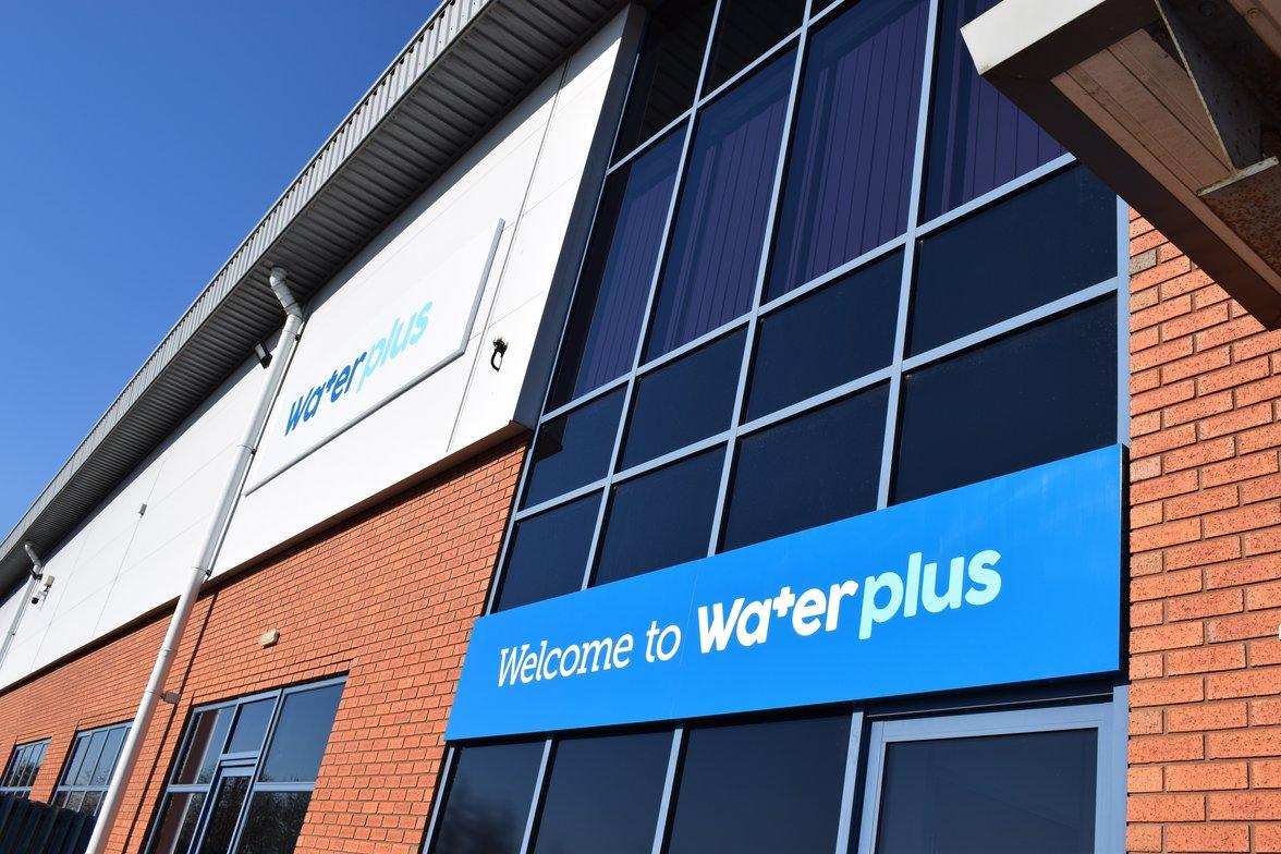 Modern Water Plus office building with brick and glass facade under a blue sky