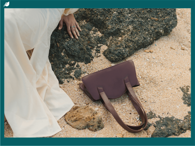 Chocolate brown vegan leather handbag on a rocky beach