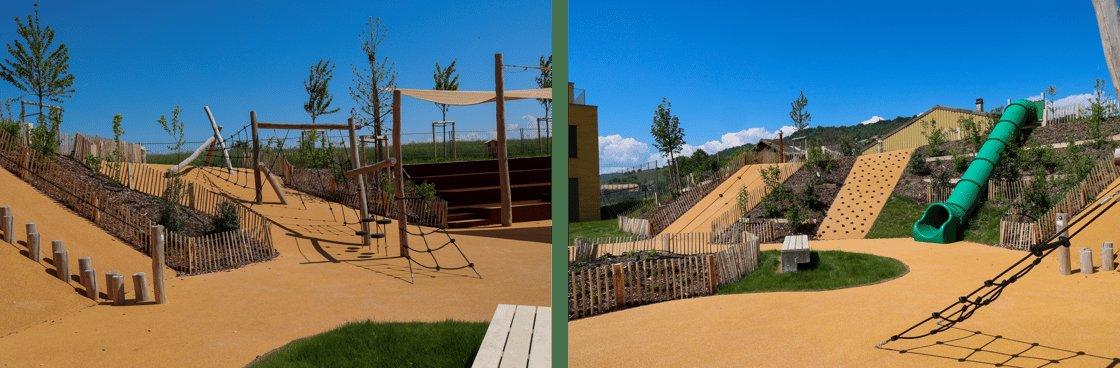 A wide shot of a modern outdoor playground with various wooden climbing structures, a green tube slide on a hill, and a climbing wall, all set on a sandy surface under a clear blue sky.