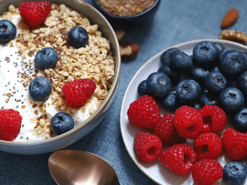 A breakfast bowl of yogurt topped with granola, seeds and berries