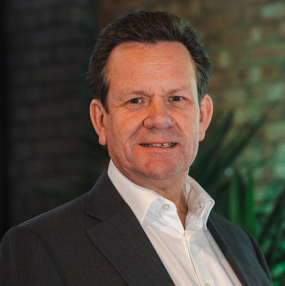 Francis Sullivan, Chair of ResponsibleGlass, photographed against a brick wall with greenery