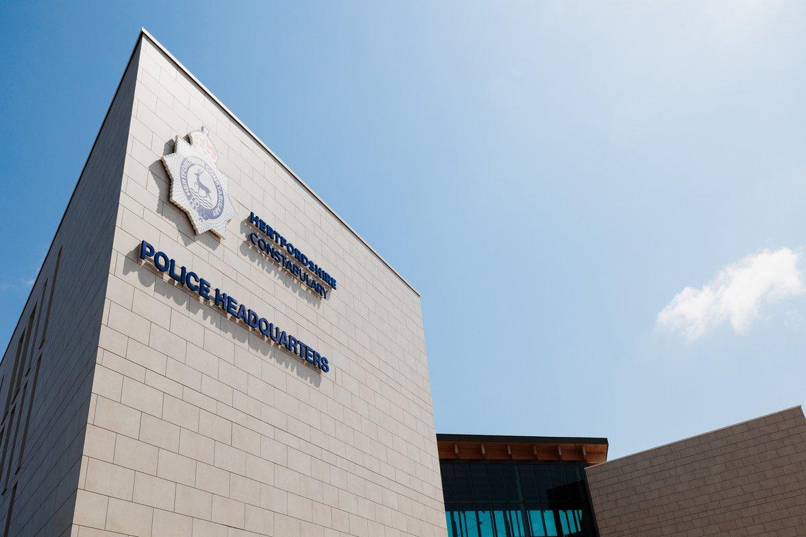 Hertfordshire Constabulary Police Headquarters building exterior with signage and police emblem under blue sky.
