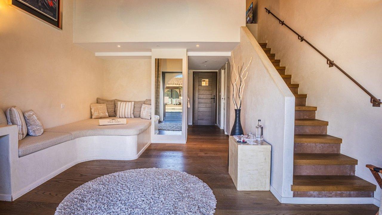 Elegant hotel lounge interior at Villa Cosy with curved sofa and mirrored doorway to outdoor terrace.