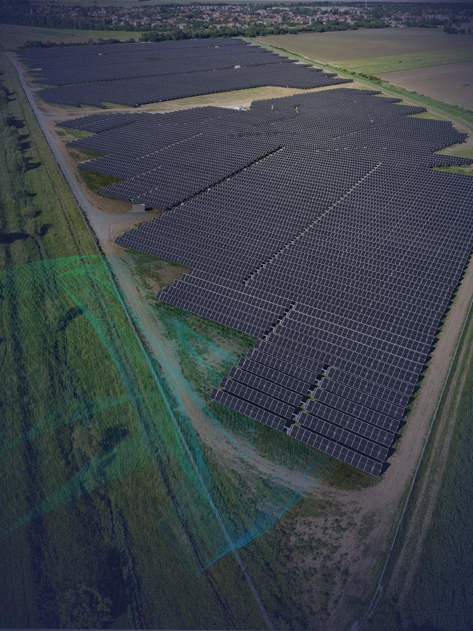 Aerial view of a large solar panel farm in Hungary with a town visible in the distance