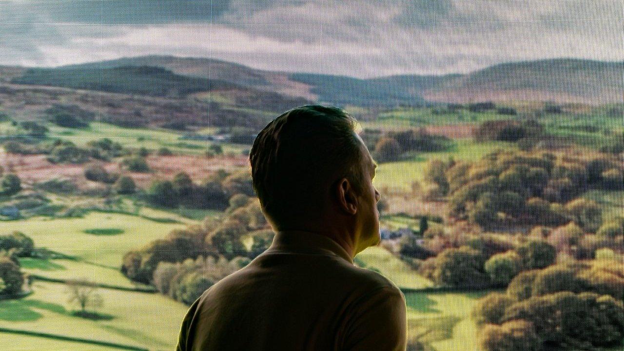 Person looking out over rolling green hills and fields of the Yorkshire Dales under a cloudy sky