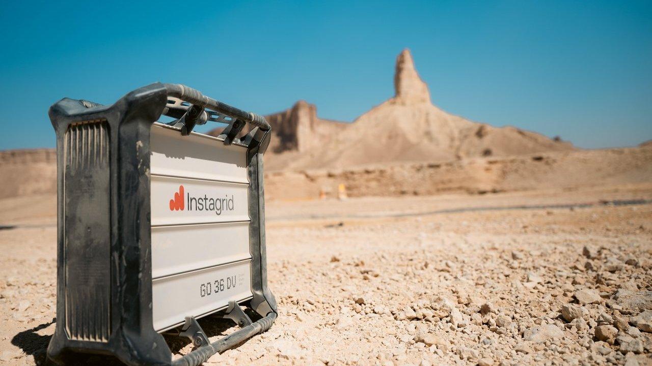 Instagrid portable power unit on desert terrain near rock formations under a blue sky