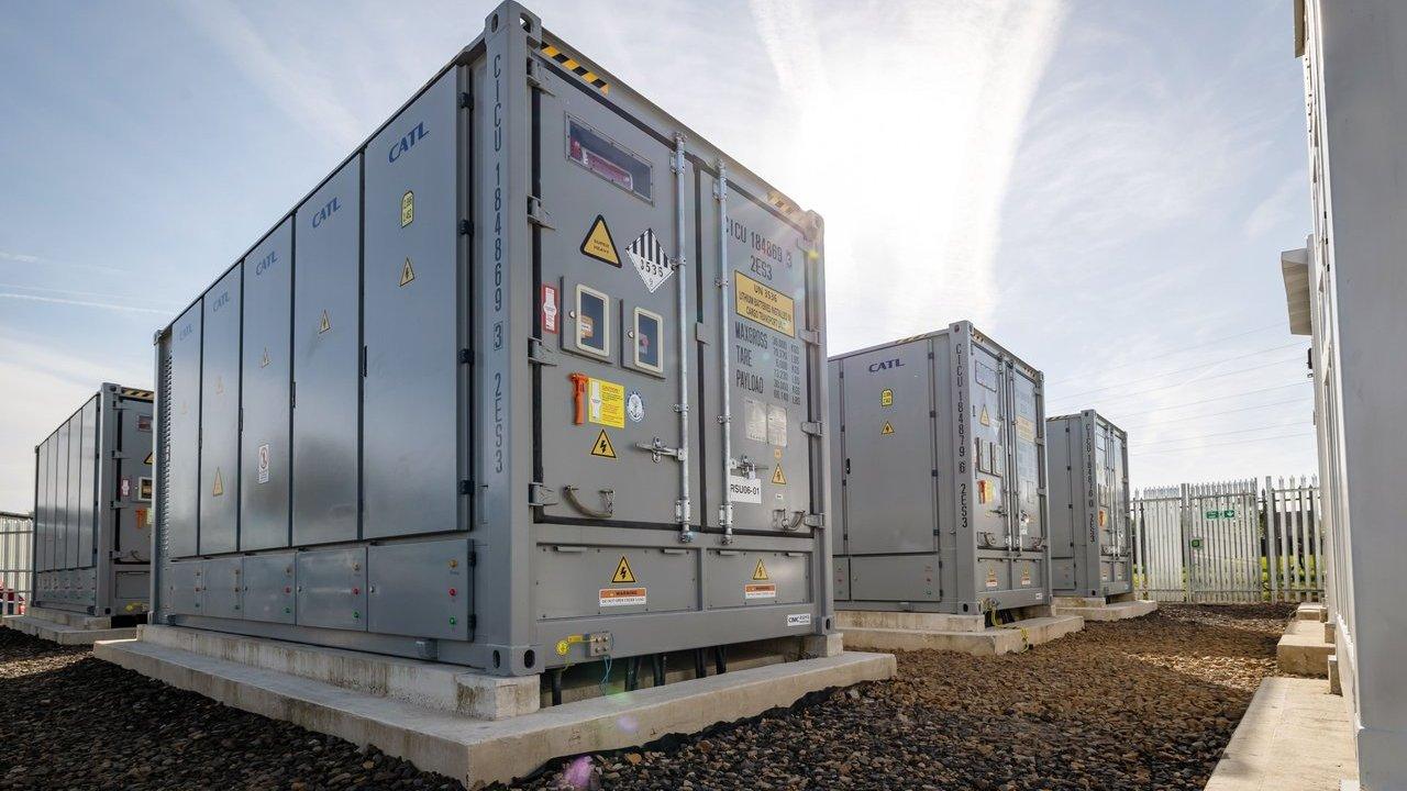 Rows of gray CATL battery energy storage containers on concrete pads beside a fenced facility