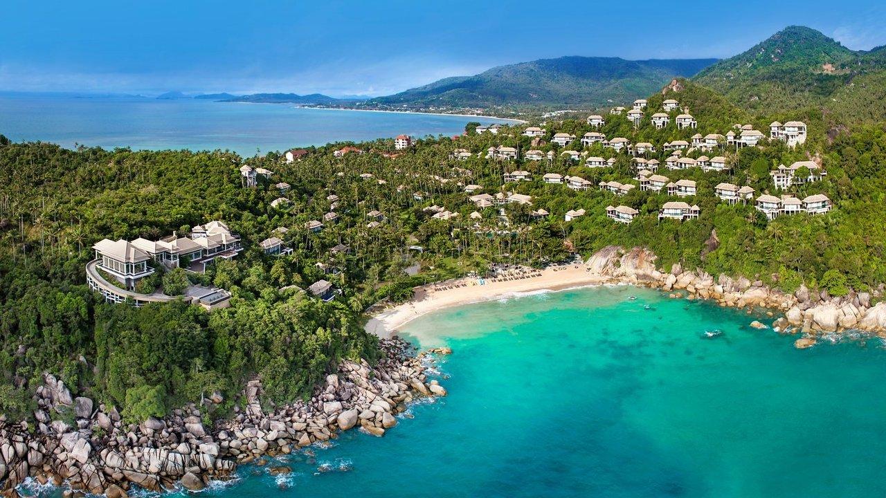 Hillside villas amid tropical forest overlooking a sandy cove and turquoise sea