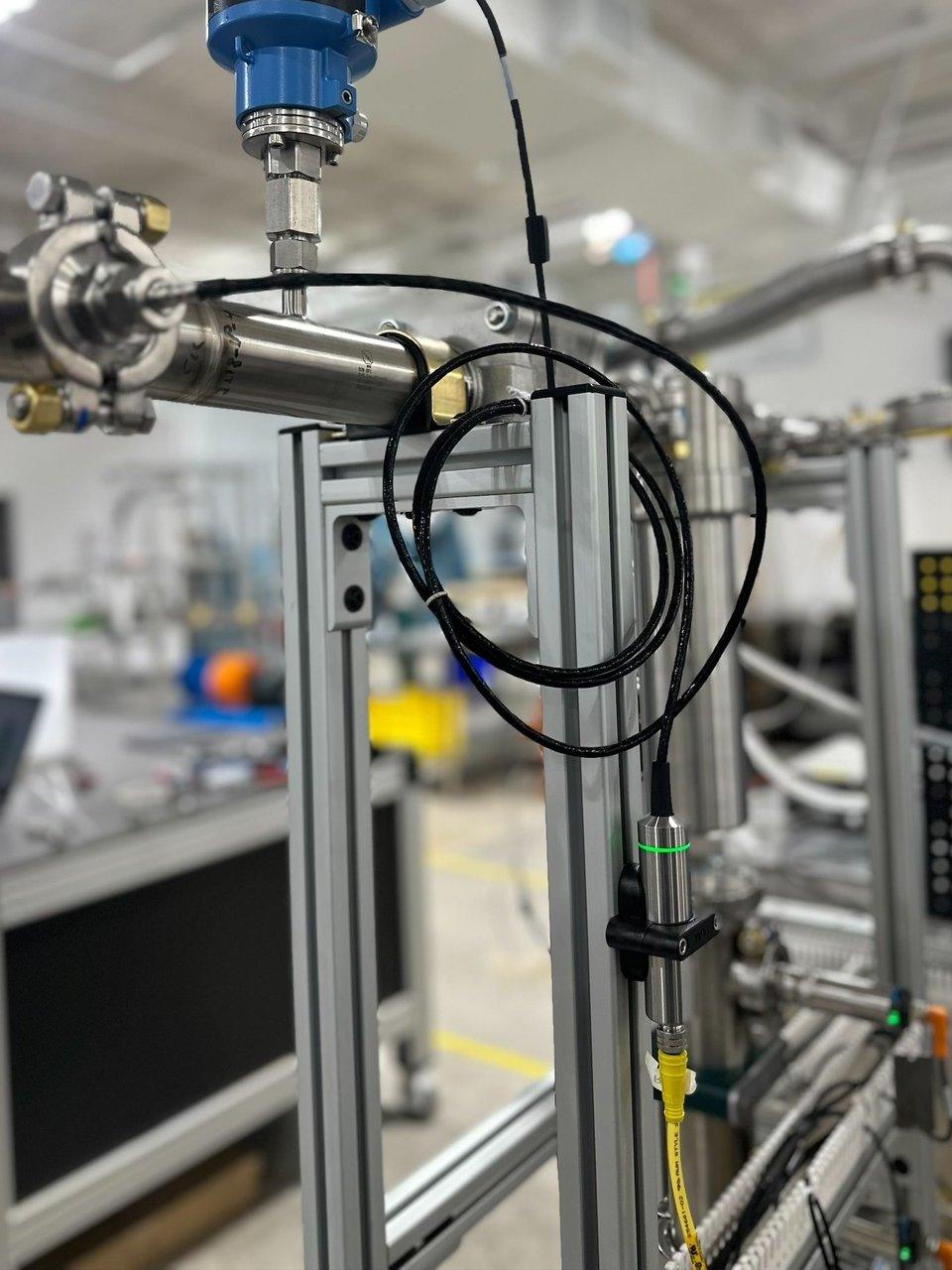 Stainless steel piping with sensors and cables mounted on an aluminum industrial test rig.